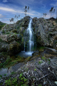 Scenic view of waterfall against sky