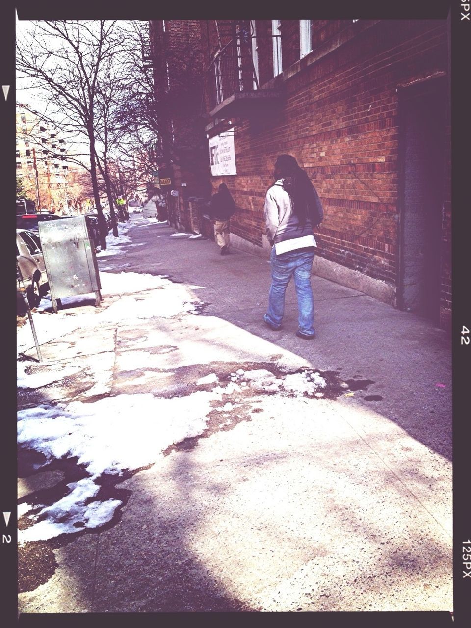 REAR VIEW OF MAN WALKING ON SIDEWALK