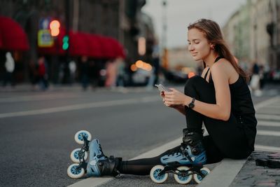 Full length of woman using smart phone on street