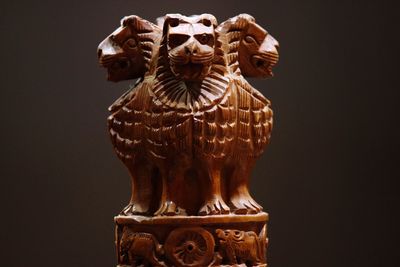 Close-up of wooden national emblem statue against gray background