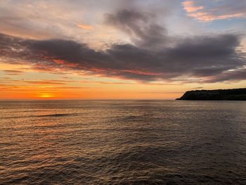Scenic view of sea against dramatic sky during sunset