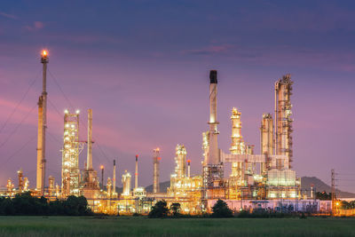 Illuminated factory against sky during sunset