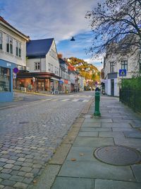 Sidewalk by buildings in city against sky