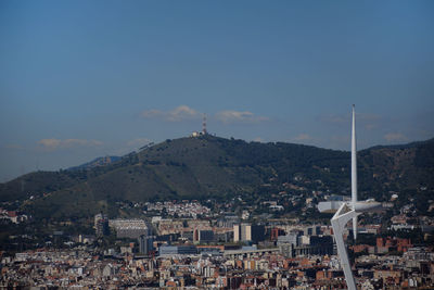 Aerial view of townscape by mountain against sky. antenna tower with barcelona city
