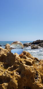 Rocks on beach against clear blue sky