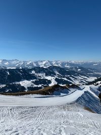 Scenic view of snow covered mountains against clear blue sky