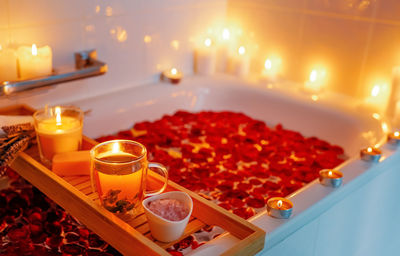 Herbal mint tea on bathtub tray with candles, lavender and salt during spiritual aura cleansing 