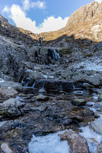 Stream flowing through rocks against sky