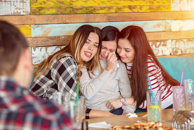 Friends consoling crying woman at restaurant