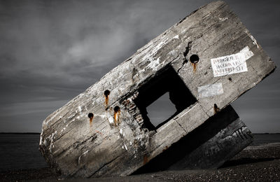 Information sign by sea against sky