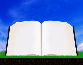 Low angle view of open book against blue sky