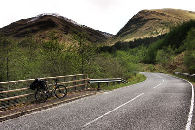 Bicycle leaning on railing against mountains