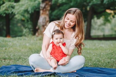 Portrait of happy mother with baby sitting outdoors