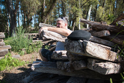 Man sitting on wooden logs in forest