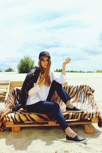 Portrait of young woman sitting on horse against sky