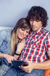 Close-up of couple using digital tablet while lying down on bed at home