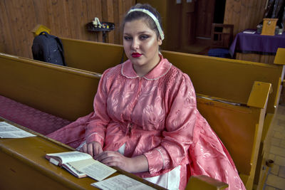 Portrait of young woman sitting on book at home