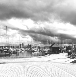 Boats moored at harbor against sky in city