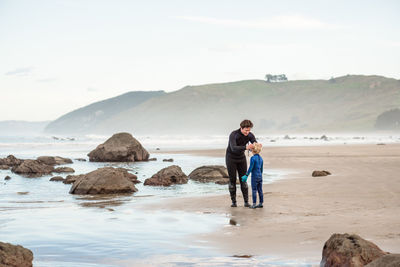 Dad helping small child put mask on at beach