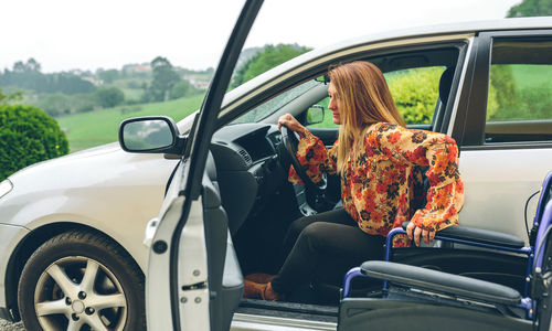 Woman sitting in car by wheelchair