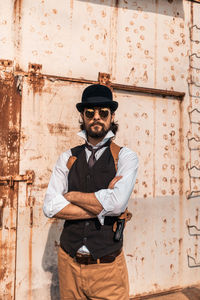 Young man wearing sunglasses standing against wall