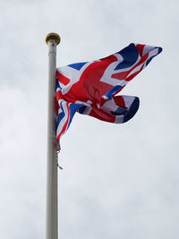 Low angle view of british flag waving against cloudy sky