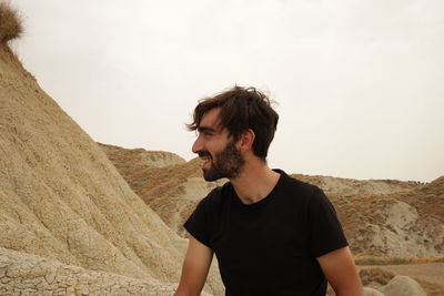 Young man looking at camera against sky