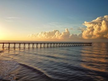 Pier over sea against sky during sunset