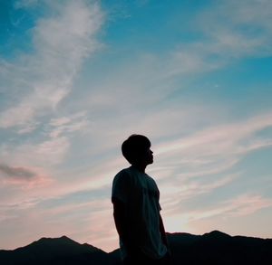 Man standing against sky and mountain during sunset