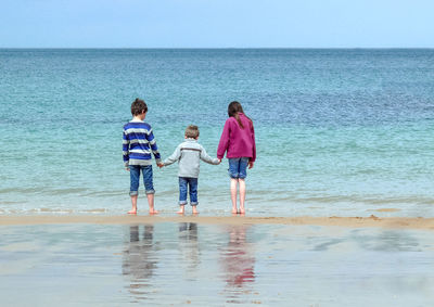 Rear view of children on beach against sky