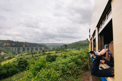 People looking at mountain through train window