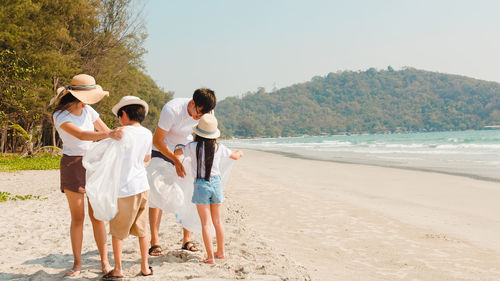 Rear view of friends standing on beach