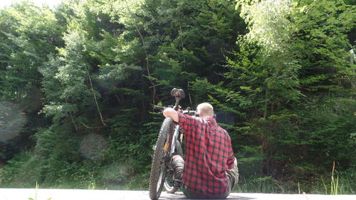 Rear view of young man standing against trees