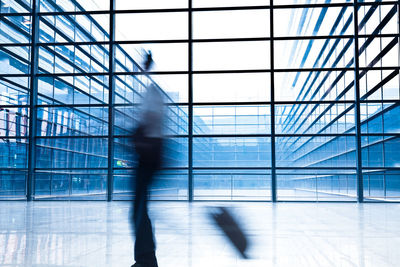 Blurred motion of people walking in glass building