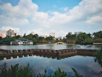 Scenic view of river by buildings against sky