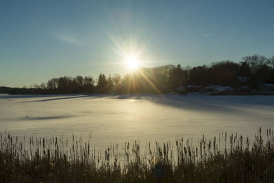 Scenic view of snow covered landscape against sky at sunset