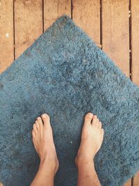 Low section of person standing on doormat over floorboard