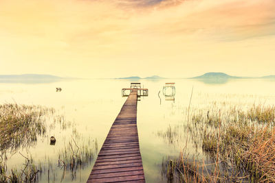 Wooden pier on lake against sky