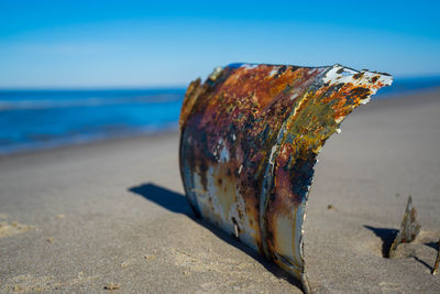 Close-up of rusty metal on beach against sky