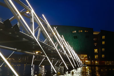 Illuminated bridge over river against sky at night