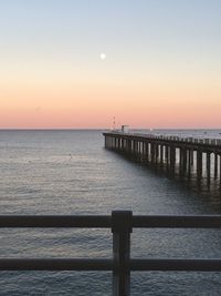 Pier over sea against clear sky during sunset