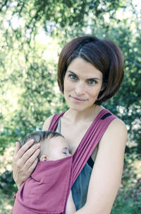 Portrait of happy mother and daughter against trees