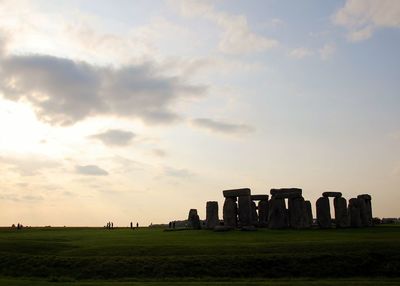 Silhouette stonehenge on field against sky during sunset