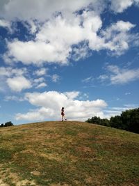 Low angle view of girl standing on mountain against sky