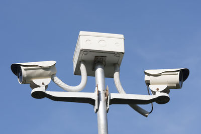 Low angle view of security cameras against sky