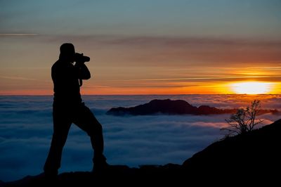 Silhouette man standing against orange sky during sunset