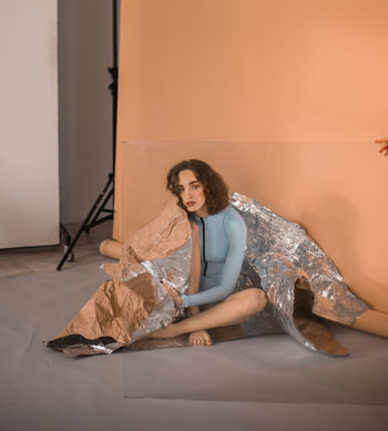 Portrait of young woman seen through glass held by cropped hand during shoot at studio