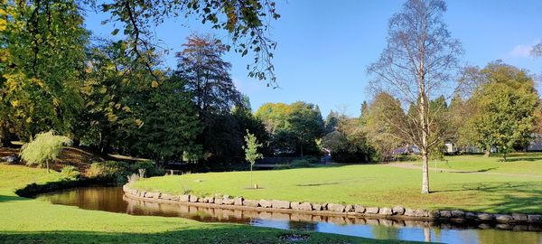 Scenic view of park by lake against sky