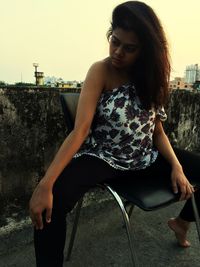 Mid adult woman sitting against sky