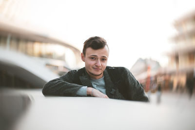 Portrait of young man sitting on car